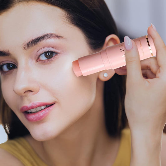 Woman applying pink makeup stick to her face